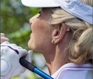 Kvinna med hörapparat som spelar golf.